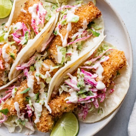 Delectable fish tacos piled high with vibrant slaw, hinting at the zesty lime and a flavorful bite.