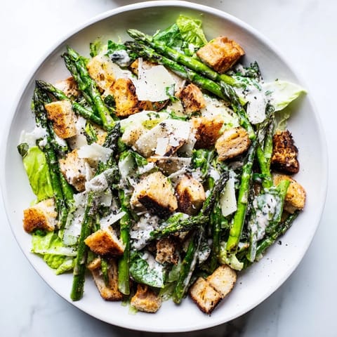 Warm, charred asparagus rests on a bed of chilled romaine with tangy yogurt dressing, finished with fresh black pepper and golden croutons.