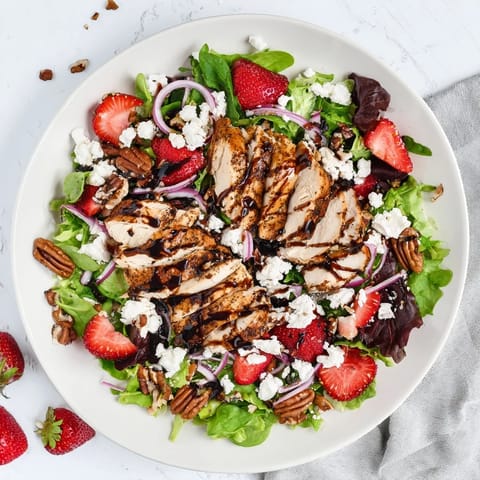 A close-up of Strawberry Balsamic Chicken Salad with toasted pecans and vibrant red onion slices.  