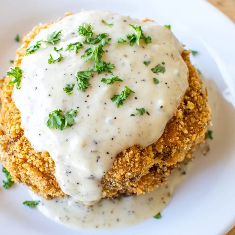 Golden-brown Chicken Fried Steak, just fried and awaiting a generous pour of creamy gravy on the plate.