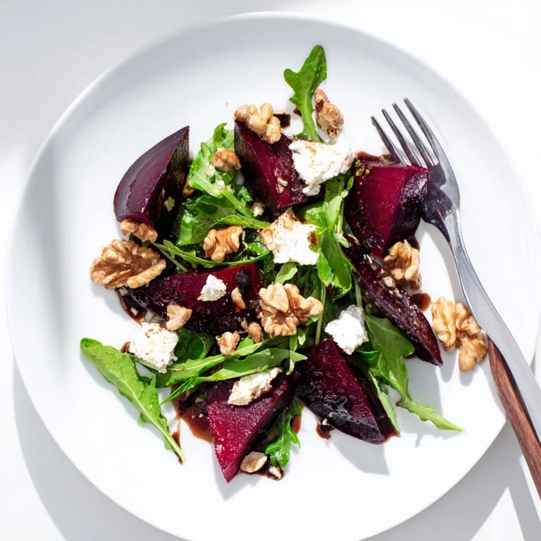 Colorful bowl of Roasted Beet Goat Cheese Salad, with warm roasted beets and toasted walnuts paired with bright greens and tangy dressing.